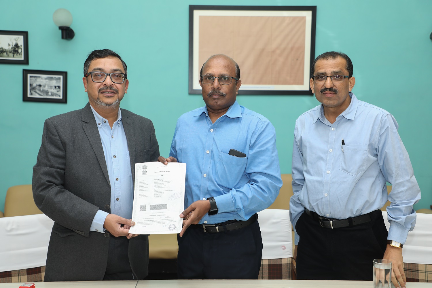 Col. (Retd.) S.D. Aravendan (centre), Chief Administrative Officer, IIMB, and Mr. Shoubhik Dasgupta (left), COO, Pi EV Solutions Pvt Ltd., an electric vehicle charging solutions provider, exchange an agreement for the installation of an EV charging station for two-wheelers and four-wheelers on campus on 12 December 2022. Mr Vasudeva M, Chief Manager, Infrastructure at IIMB, looks on.